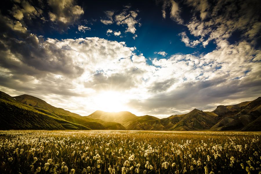 Słońce przebijające się przez chmury na tle gór w Islandii fot. Marek Kędzierski